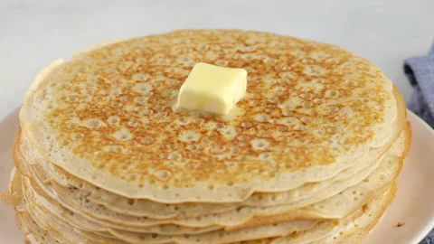 A lump of butter melts on a stack of hot pancakes. Camera movement. Big round Stock Footage 145489599
