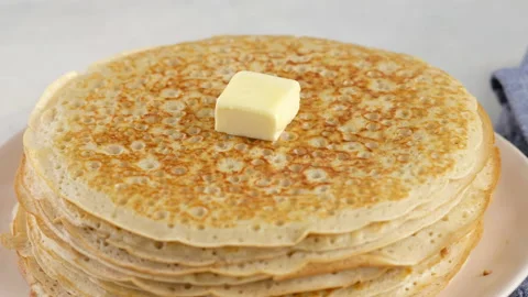 A lump of butter melts on a stack of hot pancakes. Camera movement. Big round Stock Footage 146909402