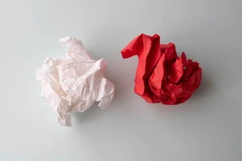 Lumps of pink and red crumpled paper lie on a white surface Foto stock