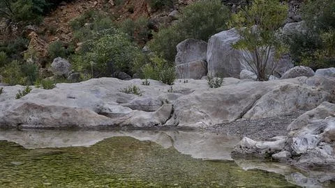 Lumps of rocks in water with reflection, Gorrori canyon Stock Photos