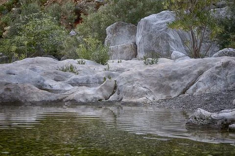 Lumps of rocks in water with reflection, Gorrori canyon Stock Photos