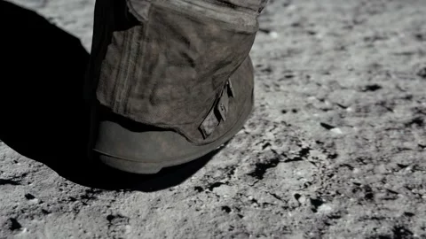 Lunar astronaut walking on the moon's surface and leaves a footprint in the Stock Footage 247311725