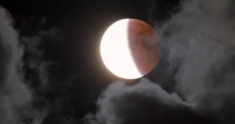 Lunar eclipse. The moon on the background of a dark sky with clouds. Stock Footage 317096399