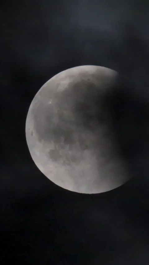 Lunar eclipse. The moon on the background of a dark sky with clouds. Stock Footage 346393724