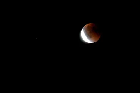 Lunar eclipse, part of the moon illuminated by the sun Fotos Stock