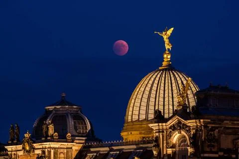 Lunar eclipse, the red moon behind the golden statue of an angel blowing i... Stock Photos