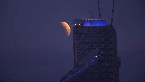 Lunar eclipse visible above Canary Wharf in London Stock Footage 304116096