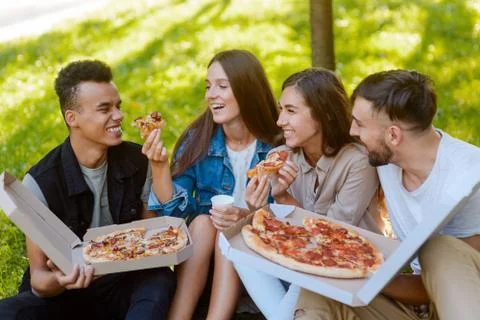 Lunch break after college classes. Friends eating pizza in the park Stock Photos