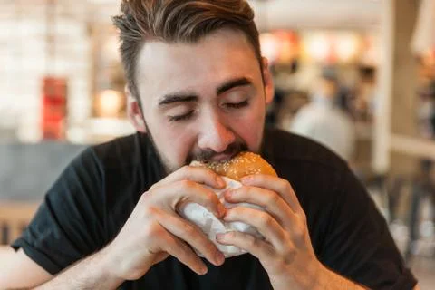 Lunch at the cafe. The man eats a burger. Stock Photos