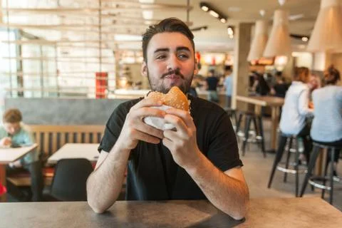 Lunch at the cafe. The man eats a burger. Stock Photos