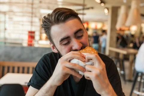 Lunch at the cafe. The man eats a burger. Stock Photos