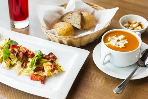 Lunch on the table: tomato puree soup, salad of fresh vegetables and sun-drie Stock Photos