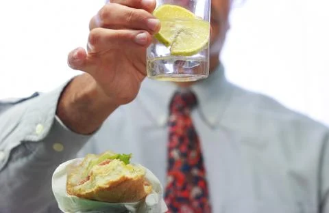Lunch time, blurred man with sandwich and glass of water Stock Photos