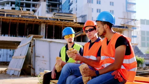 At the lunch time in the mi of a big construction site multiethnic workers in a Stock Footage 146603445