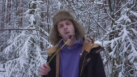 Lunch in Winter Forest. A man eats a sausage on a twig Stock Footage 82959234
