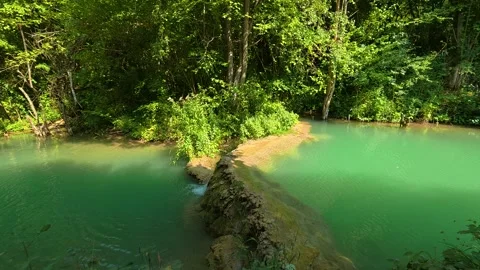 Lush forest surrounds emerald-green pool. Bigar Waterfall, Serbia 動画素材 346249729