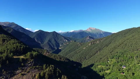 Lush forested mountain valley in Andorra under a clear blue sky, with layered Stock Footage 342479005