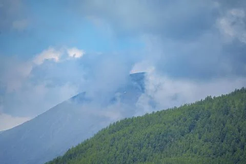 Lush forested mountains under a cloudy sky Stock Photos