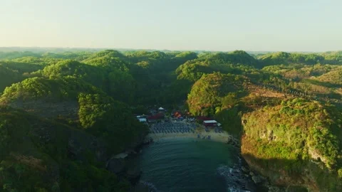 Lush green cliffs surround a tranquil coastal lagoon in an elevated aerial .. Stock Footage 341544468