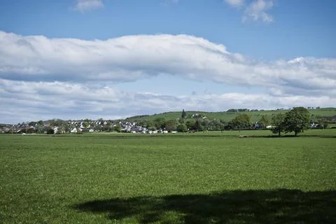 Lush green fields stretch under a bright blue sky looking over to Troon. Stock Photos
