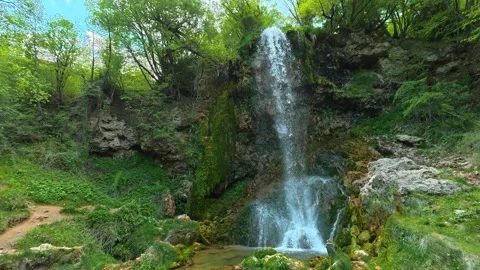 Lush green forest surrounds cascading waterfall. Gostilje Waterfall, Serbia. Stock Footage 337060236