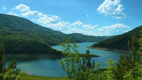Lush green hills frame a tranquil lake. Zavoj Lake, Serbia Stock Footage 337494212