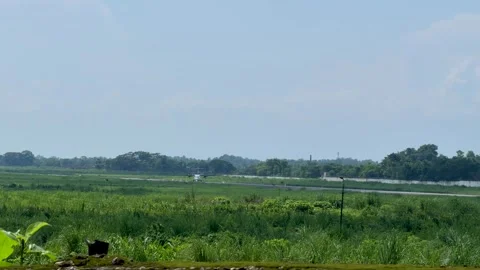 Lush green landscape with distant airplane on runway under clear blue sky Stock-Footage 339369236
