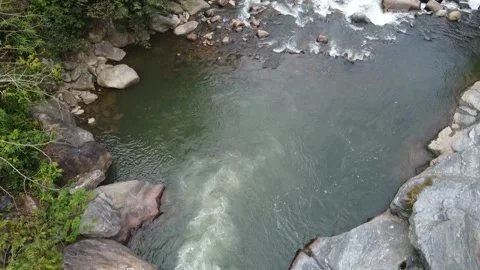 Lush green landscape featuring a serene river flowing through rocky terrain Stock Footage 297239592
