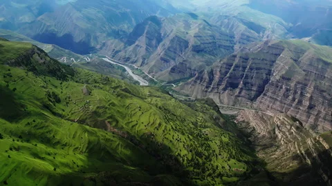Lush green mountains with terraced fields, a winding river, and roads under Stock Footage 265911238