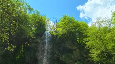 Lush green trees frame a gentle waterfall. Gostilje Waterfall, Serbia. Stock Footage 337059914