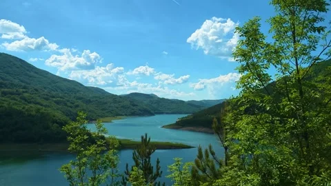 Lush green trees frame a serene mountain lake. Zavoj Lake, Serbia Stock Footage 337494040