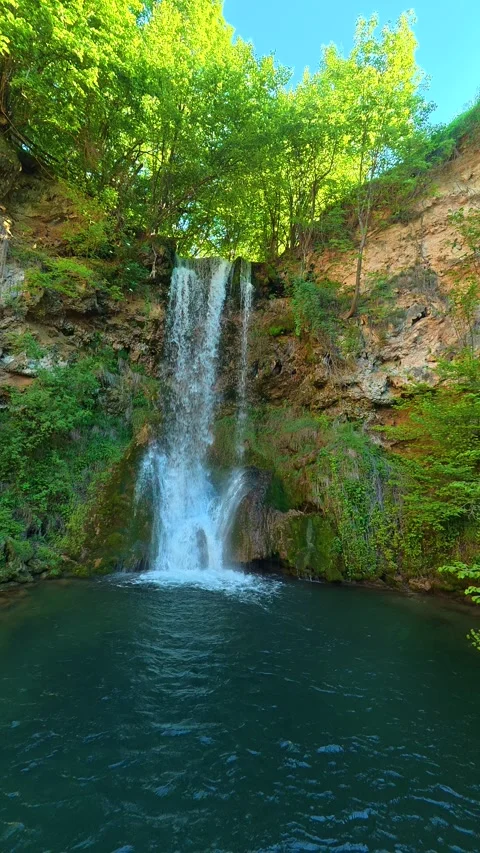 Lush green trees surround a gentle waterfall. Veliki Buk, Serbia. Vertical Vídeos de archivo 336890618