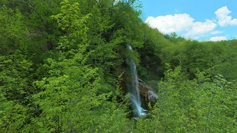 Lush green trees surround a gentle waterfall. Gostilje Waterfall, Serbia. Stock Footage 337059598