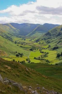 Lush green valley with a patchwork of rolling hills and lush grassy fields. Stockfoto's