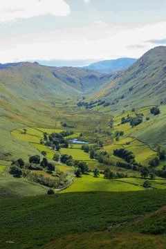 Lush green valley with a patchwork of rolling hills and lush grassy fields. Stock Photos