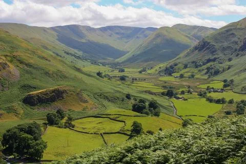 Lush green valley with a patchwork of rolling hills and lush grassy fields. Stock-Fotos