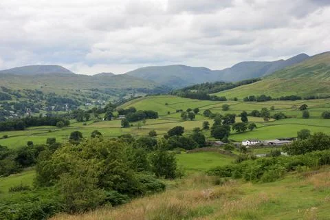 Lush green valley with a patchwork of rolling hills and lush grassy fields. Stock Photos
