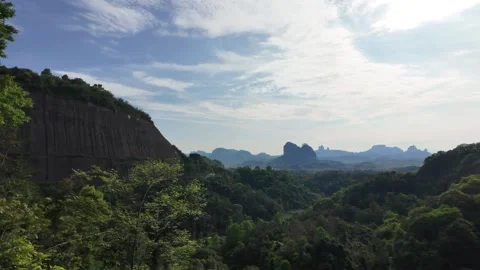 Lush green valley surrounded by steep rocky mountains under a bright blue sky Stock Footage 339265782
