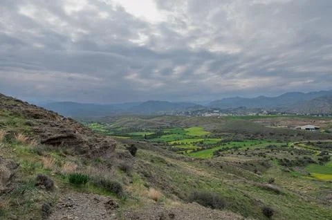Lush green valley under dramatic clouds showcases nature's serenity near a .. Foto stock