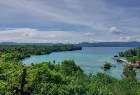Lush greenery frames turquoise waters under a soft blue sky 库存照片