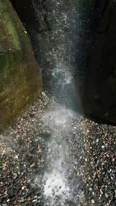 Lush Waterfall with Rainbow Mist Over Pebble Pool Stock-Footage 339883230