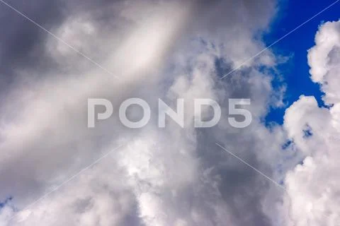 Lush white cumulus clouds swim across the blue sky Stock Photos
