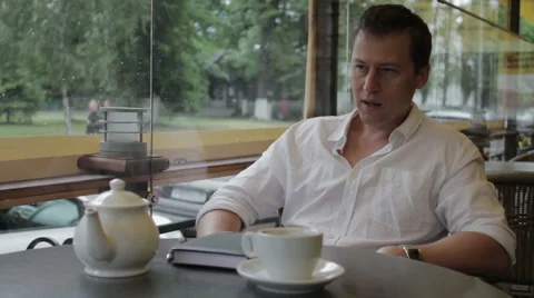 Lustful man sitting in a summer cafe and watching the passing girls Stock Footage 68175339