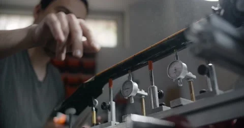 Luthier brushes off the wood dust from sanded guitar neck, works at the musical Stock Footage 165217232
