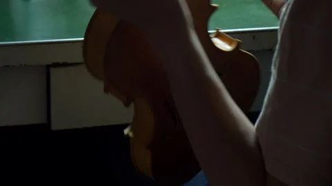 Luthier brushing warm varnish on violin body creating rich amber antique finish Stock Footage 331199550