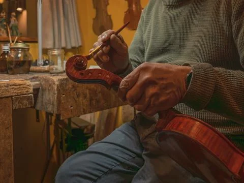 Luthier carefully applying varnish to the scroll of a classic handmade viol.. Stock Photos