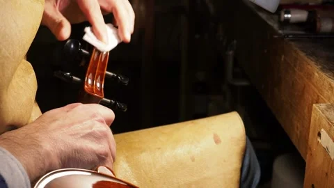 Luthier carefully polishing the scroll of a violin using a white cloth, Stock Footage 304641892