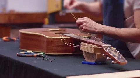Luthier changes the strings of an acoustic guitar Stock Footage 102057840