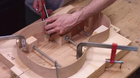 Luthier constructs an acoustic guitar in his shop Stock Footage 112006354