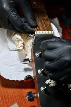 Luthier Hands in Black Gloves Installing New String on Acoustic Guitar Headstock Stock Photos